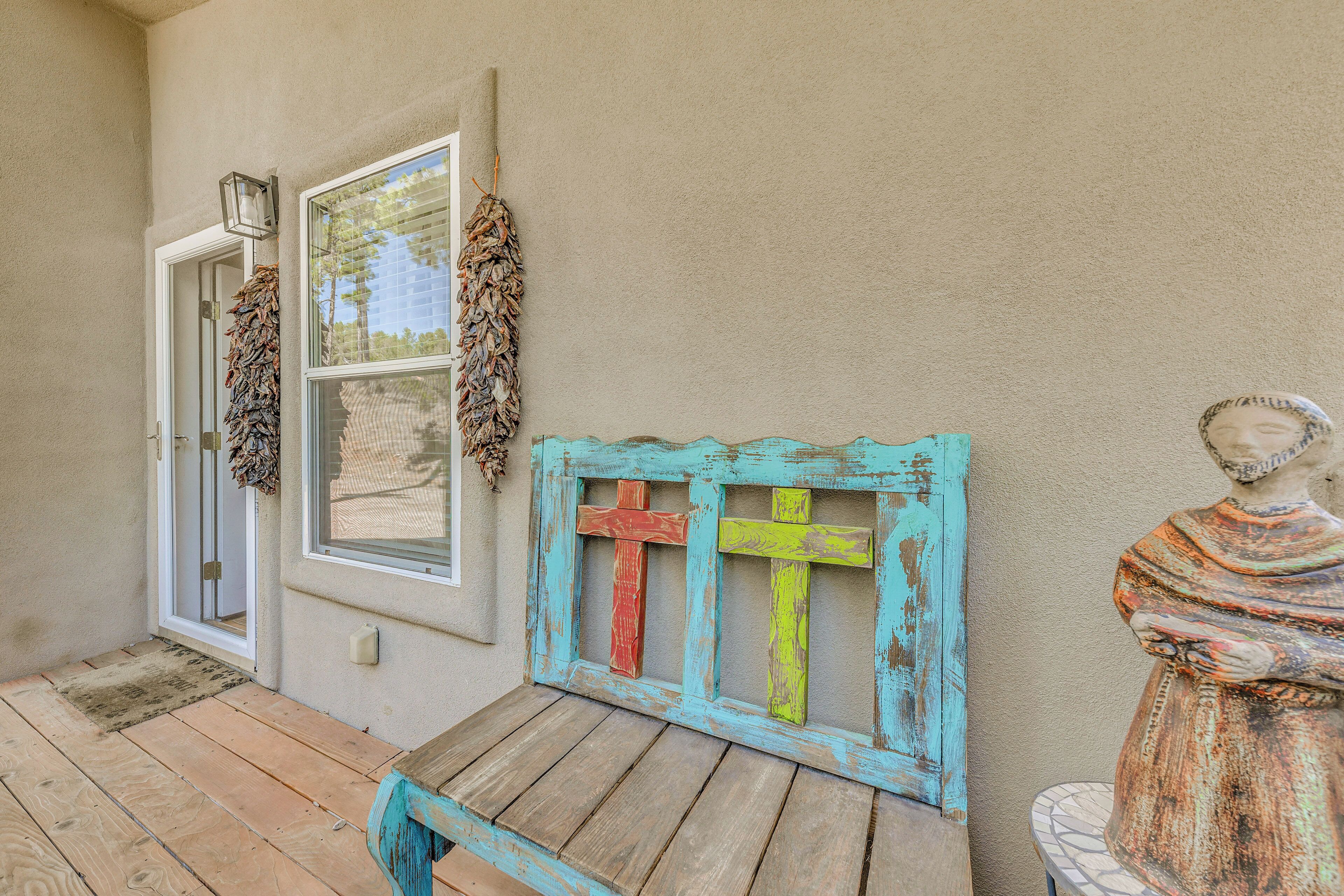 A wooden bench with a rustic design, a door, and a wall-mounted cross.