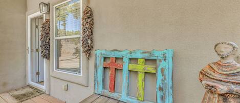A wooden bench with a rustic design, a door, and a wall-mounted cross.
