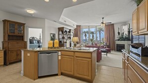 A spacious kitchen with wooden cabinets, a central island, and a dishwasher. - The Moorings 103 3 Bedroom Condo by RedAwning (Orange Beach)