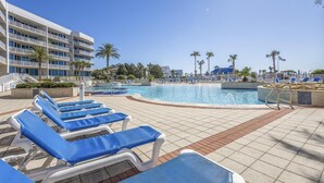 A pool area with blue lounge chairs and a modern building in the background. - The Moorings 103 3 Bedroom Condo by RedAwning (Orange Beach)