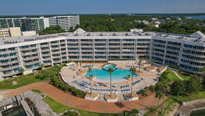 A large hotel with multiple floors, a central swimming pool, and outdoor seating areas. - The Moorings 103 3 Bedroom Condo by RedAwning (Orange Beach)