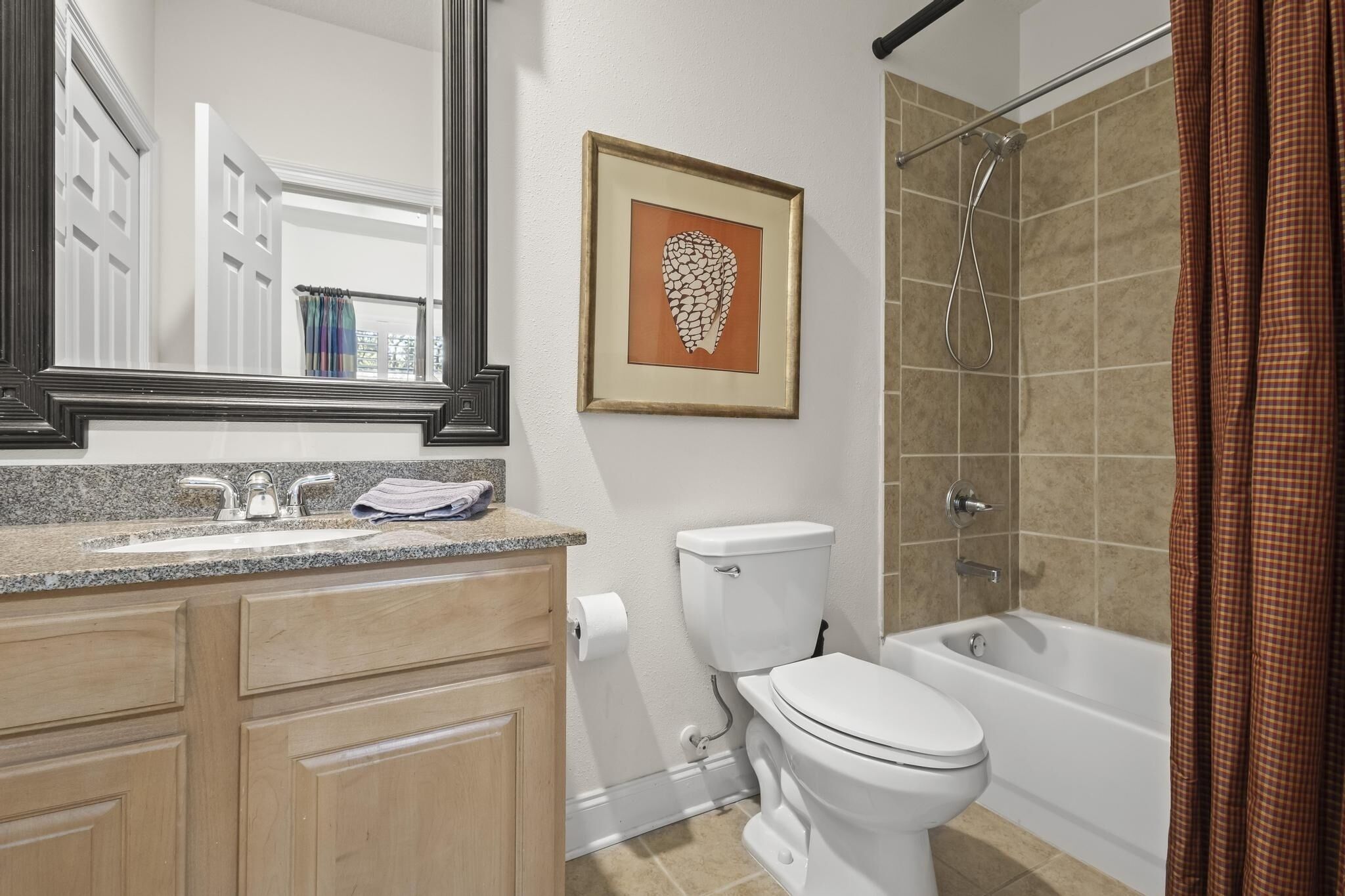 A bathroom with a sink, toilet, bathtub, and a framed artwork on the wall.