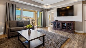 A spacious living room with a sofa, coffee table, and a flat-screen TV mounted on the wall. - Sunset Point #w302 3 Bedroom Condo (St. George)