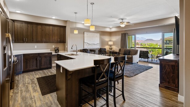 A modern kitchen with a large island, dark wood cabinets, and a view to a balcony. - Sunset Point #w302 3 Bedroom Condo (St. George)