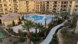 A hotel courtyard with a swimming pool, lounge chairs, and palm trees. - Sunset Point #w302 3 Bedroom Condo (St. George)
