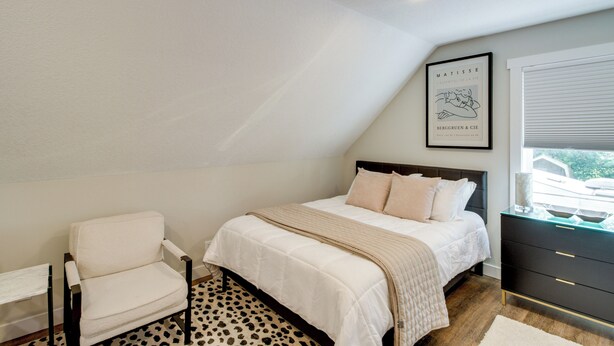 A bedroom with a bed, a chair, a window with blinds, and a framed artwork on the wall. - Stylish 'crosby Cottage' - 1 Mi to Serpent Lake! (Crosby)