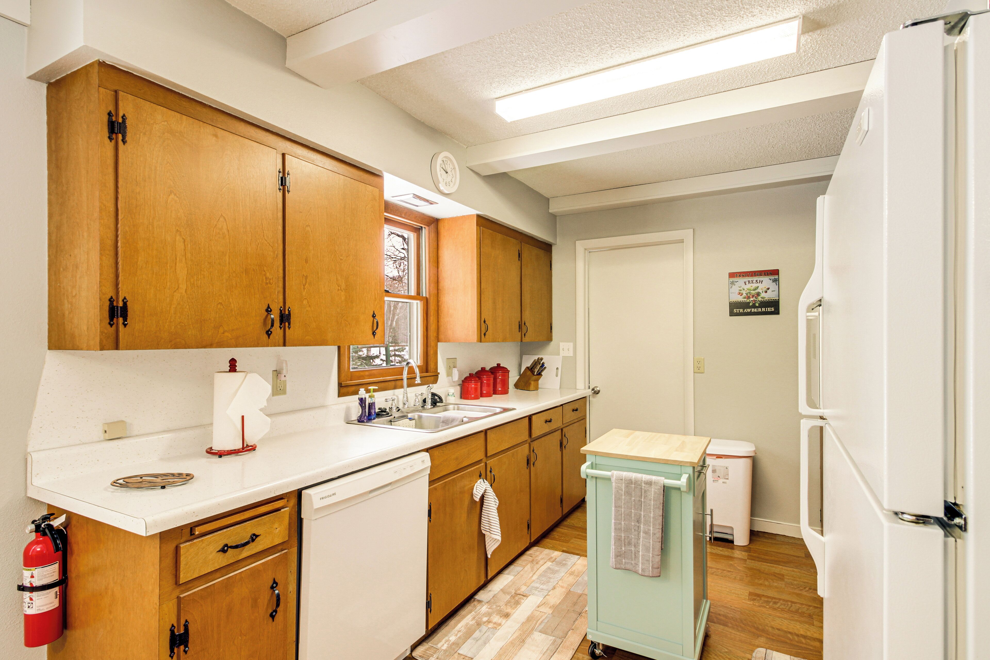 A kitchen with wooden cabinets, a white countertop, a dishwasher, a sink, and a small refrigerator.