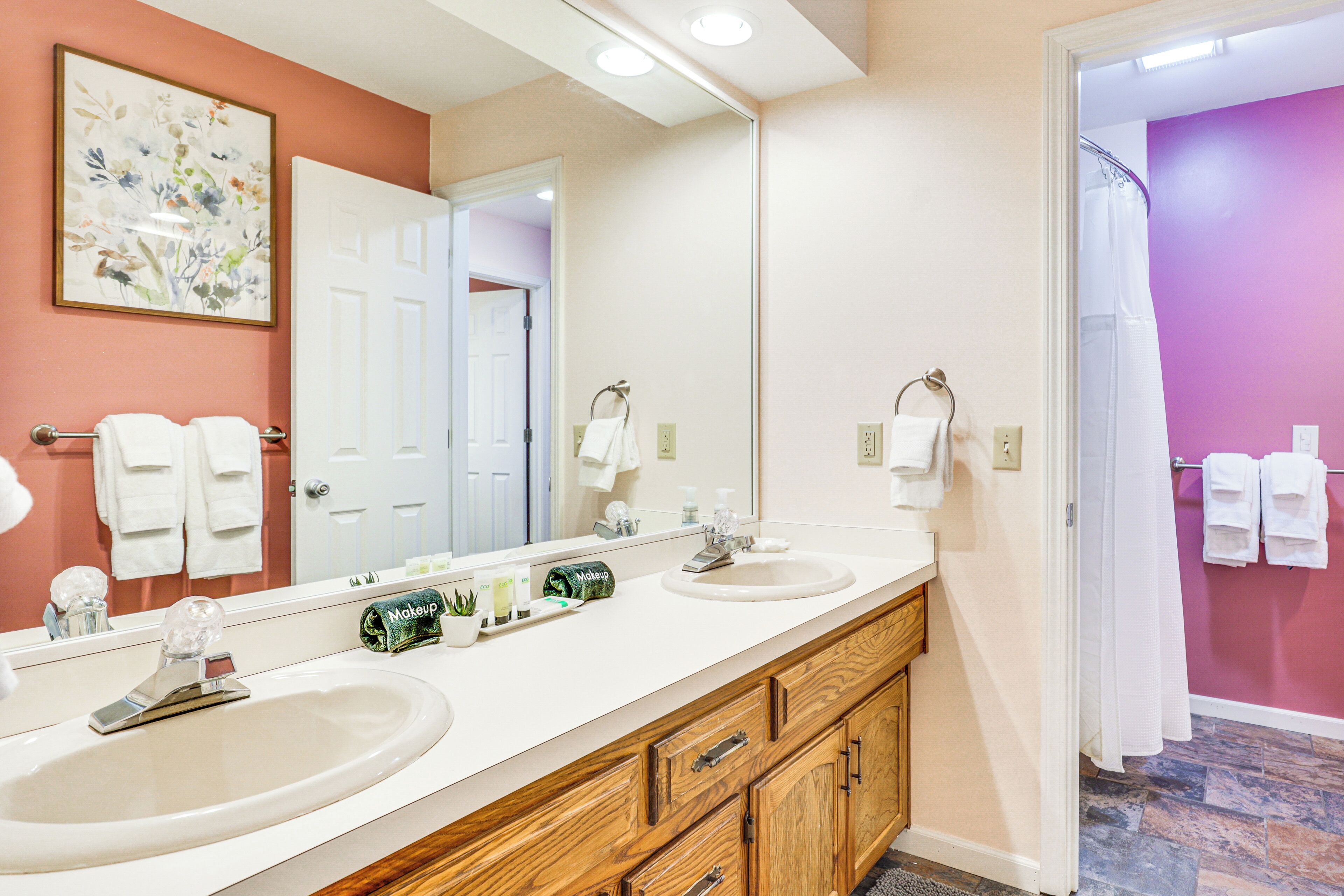 A bathroom with two sinks, a large mirror, and a shower area.