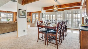A spacious dining area with a long wooden table set for six, flanked by large windows and a view of the outdoors. - Private Dock & Ozarks Shoreline: 5BR Lake House (Roach)