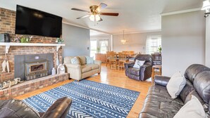 A spacious living room with a fireplace, leather sofas, a flat-screen TV, and a dining area with wooden furniture.