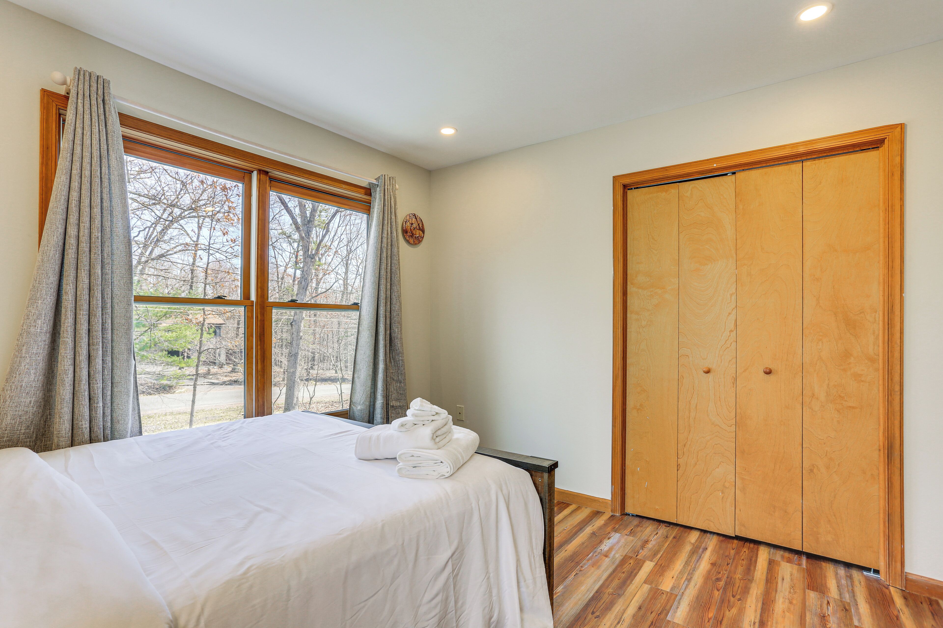A bedroom with a bed, a wooden wardrobe, and a window with curtains.