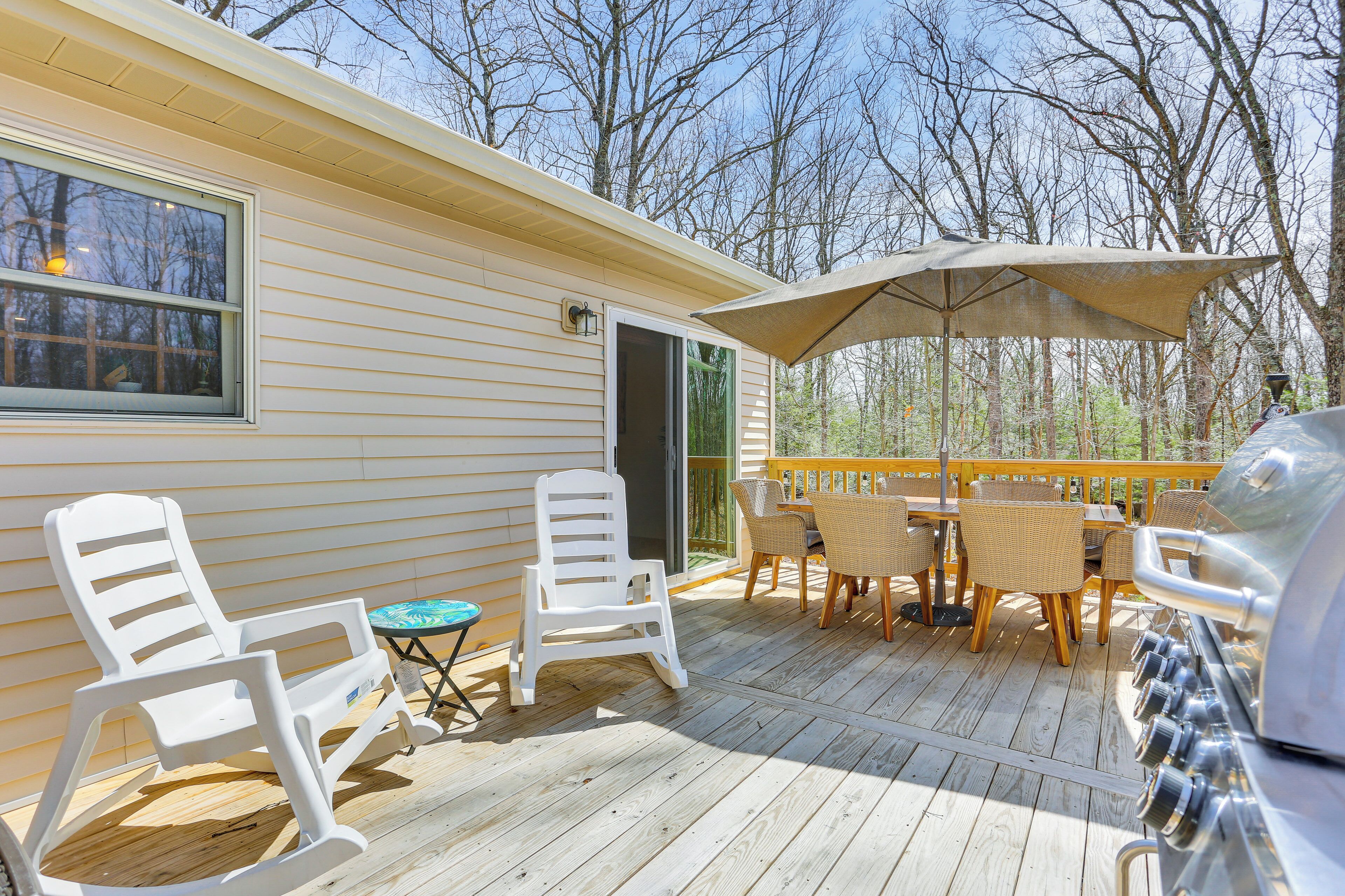A deck with outdoor furniture, including chairs and a table, and a grill.