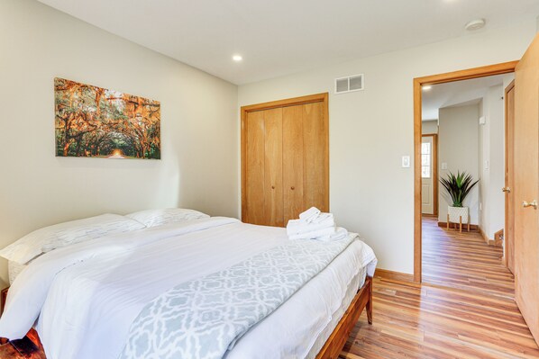Un dormitorio con una cama grande, un armario de madera y un pasillo que conduce a otra habitación.