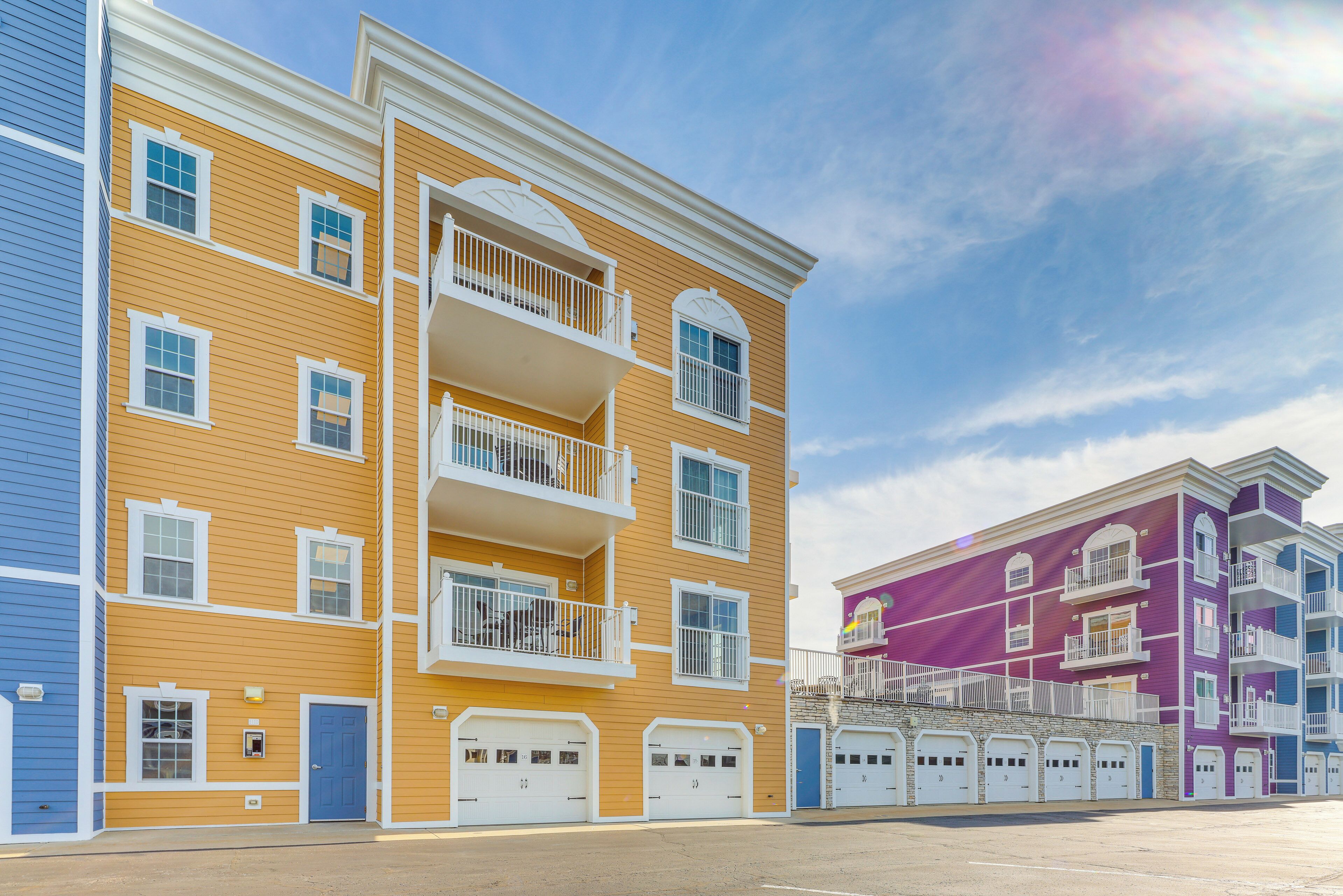 Un edificio de apartamentos de varios pisos con balcones, un garaje y un cielo despejado.