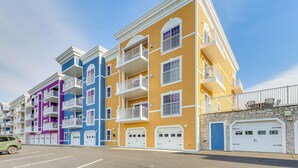 Un edificio residencial de varios pisos con balcones, fachada de piedra y zona de estacionamiento.
