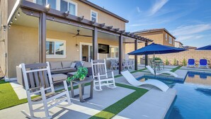 A backyard with a pool, outdoor furniture, and a pergola.
