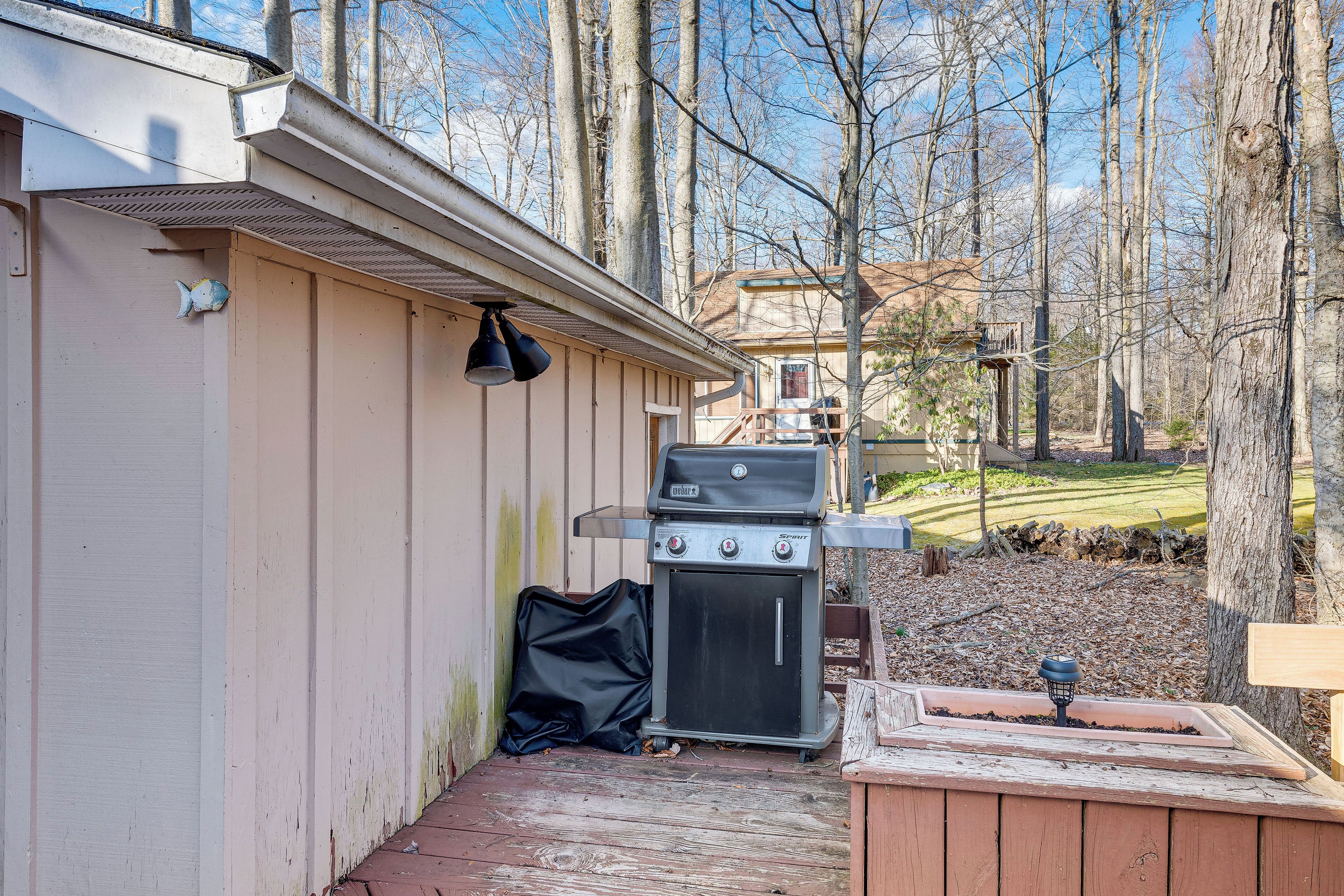 A backyard with a grill, a small oven, and a wooden deck.