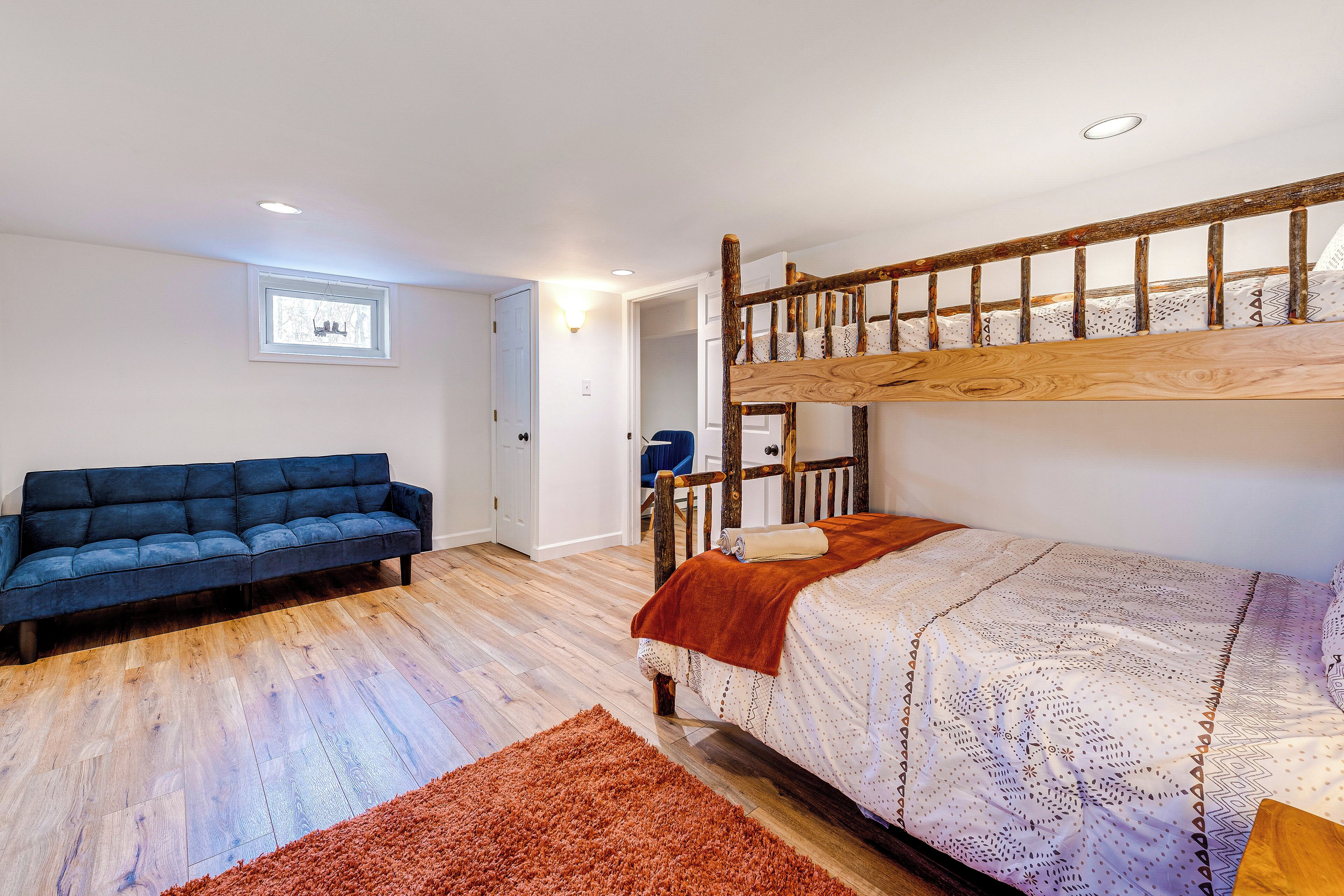 A bedroom with a bunk bed, a sofa, and a wooden floor.