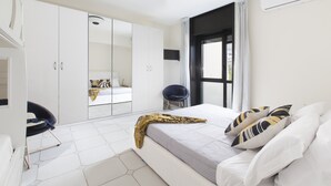 A modern bedroom with a large bed, a wardrobe, and a seating area. - Estate4home - Maison Wally (Sorrento)