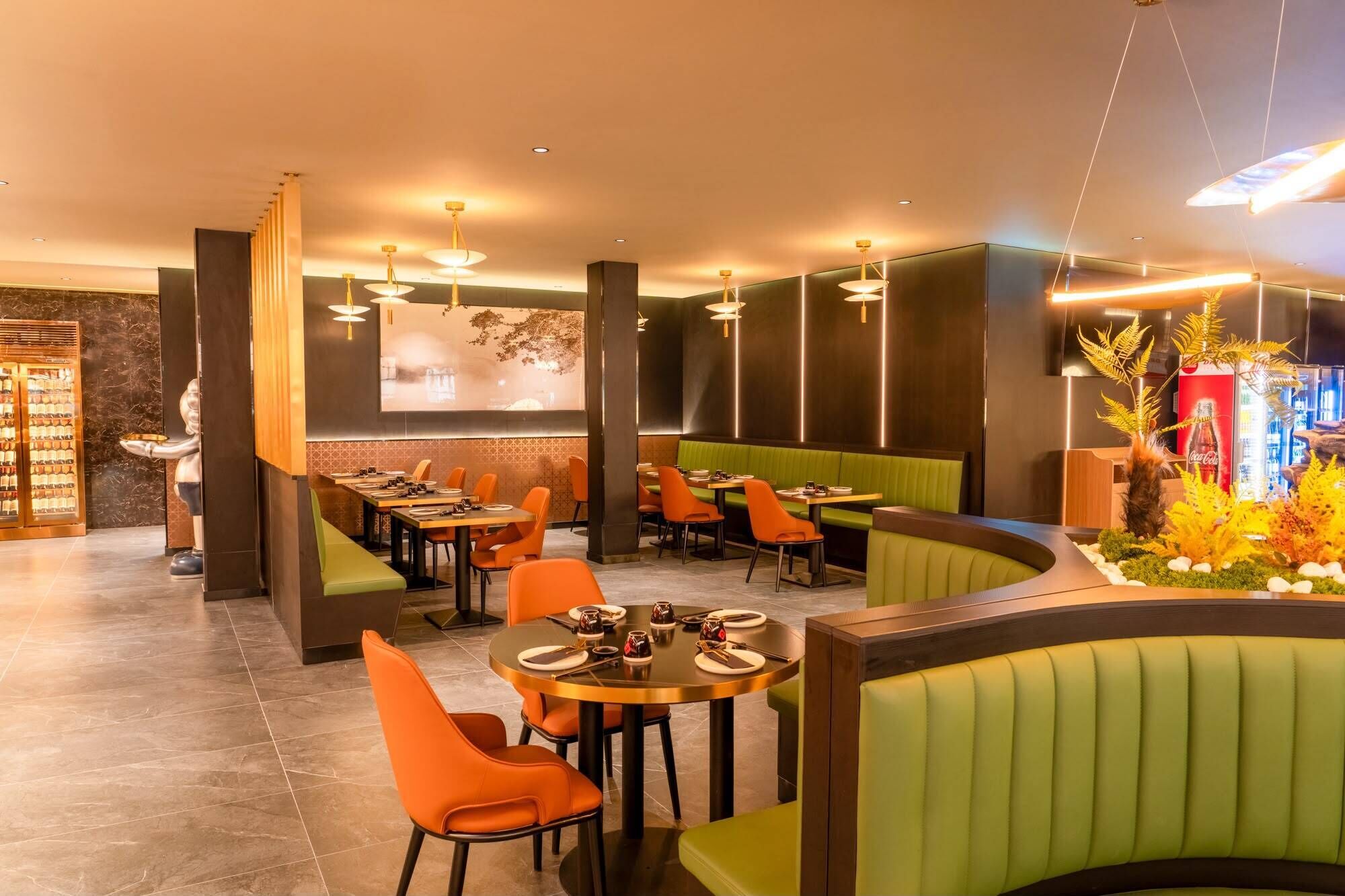 Een restaurant met zitjes, tafels, een bar en een decoratieve plantenwand.