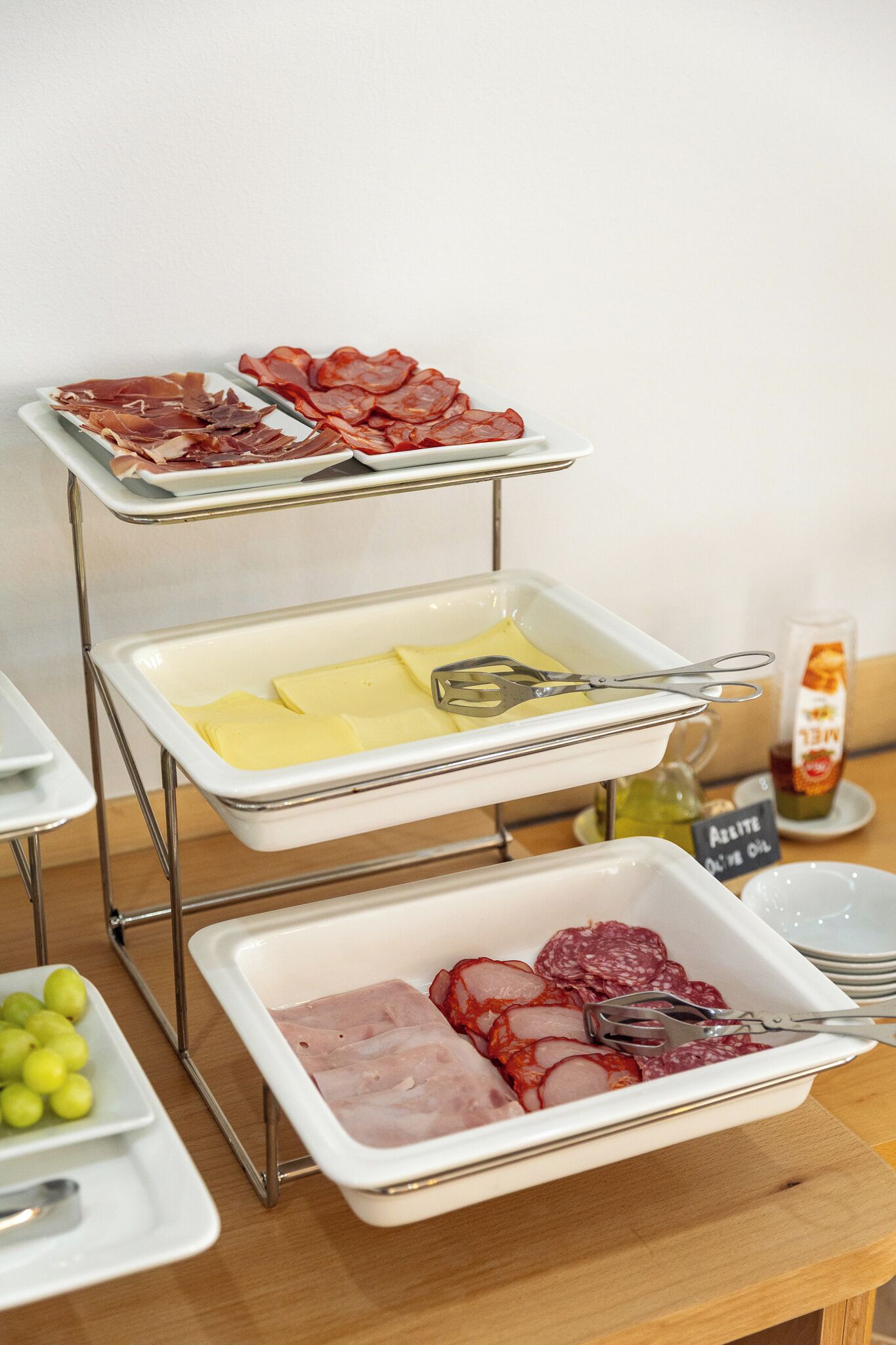 A buffet setup with trays of meats, cheese, and ham.