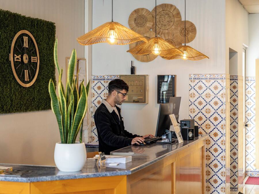 A reception desk with a clock, potted plant, and decorative wall panels.