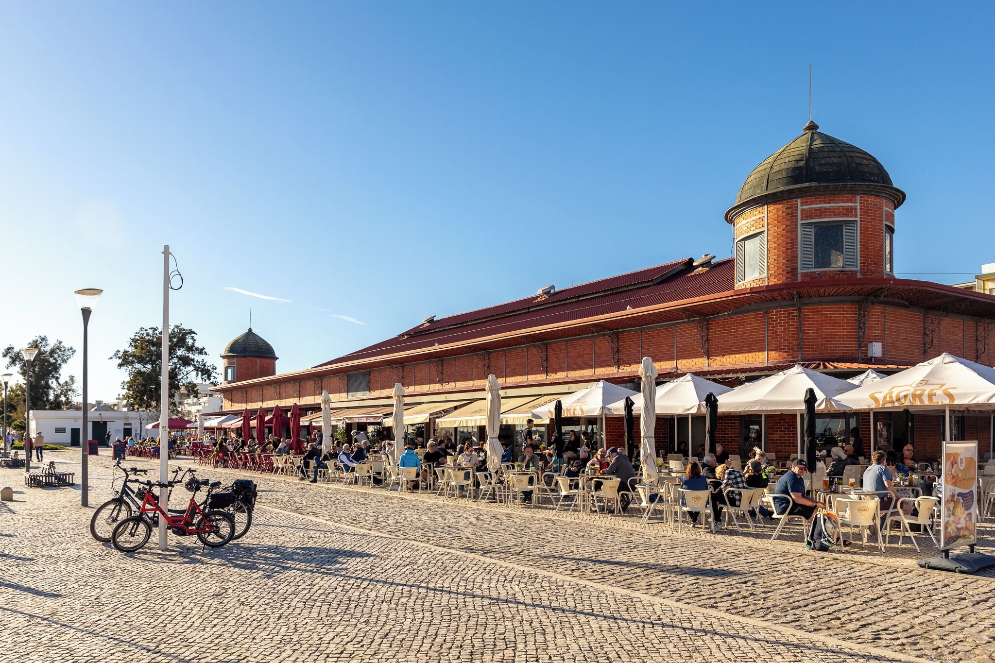 A cobblestone plaza with outdoor seating and a brick building with a dome.