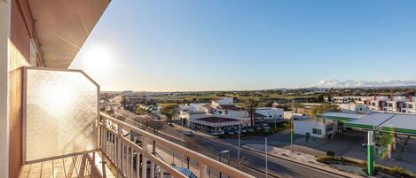 Un balcón con vista a una estación de servicio y edificios circundantes.