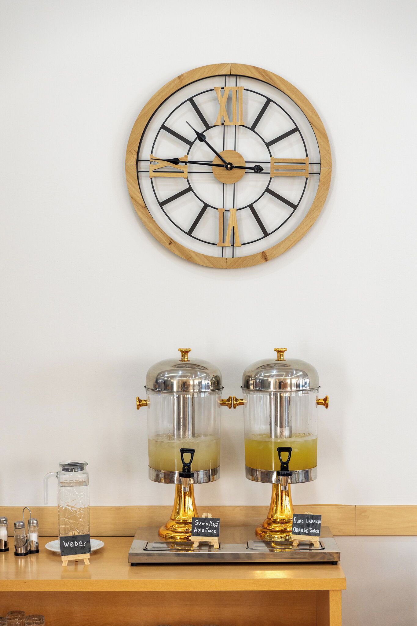 Un reloj de pared con números romanos, dos dispensadores de bebidas etiquetados como 