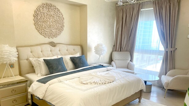 Une chambre à coucher avec un grand lit, une chaise, une table de chevet et un élément décoratif mural.