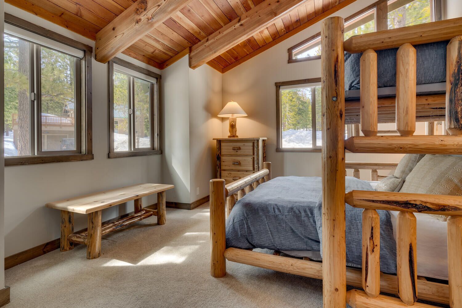 A bedroom with a wooden bed, a bench, and a dresser.