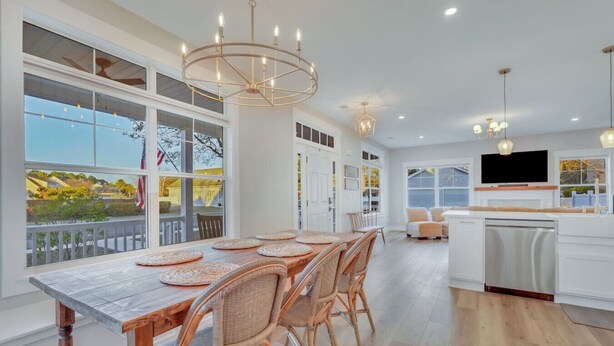 Une cuisine moderne avec une grande table à manger, des chaises en osier et une vue sur l’extérieur.