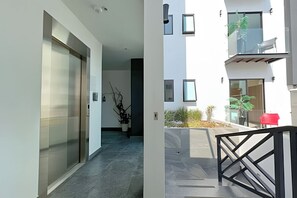 Stylish living space with a hallway leading to a door and a balcony with a chair.