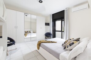 Une chambre moderne avec un grand lit, une armoire et un coin salon.