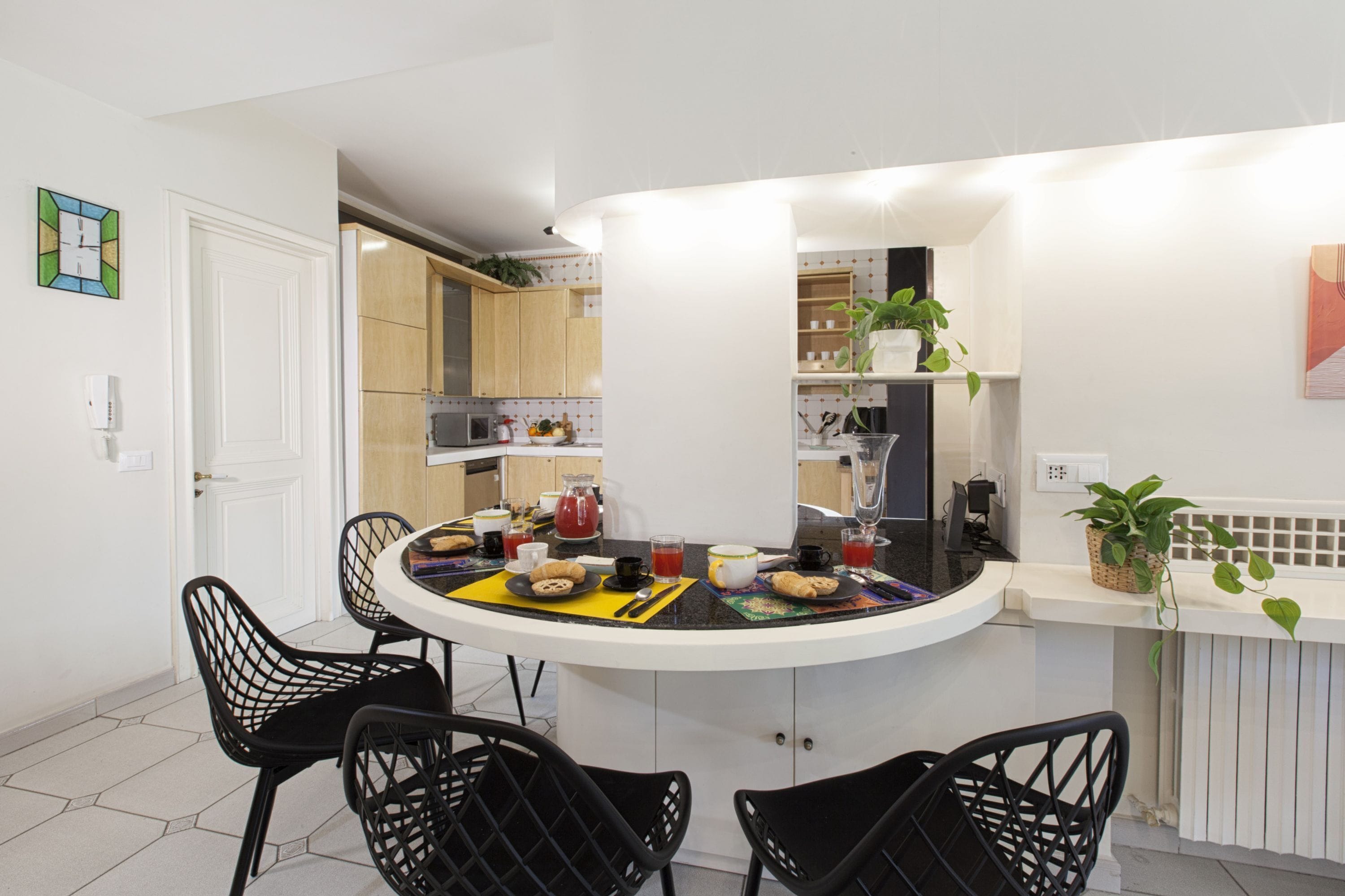 A modern kitchen with a central island, black chairs, and a dining table.