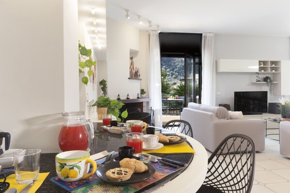 Ein modernes Wohnzimmer mit Essbereich, ausgestattet mit einer Couch, einem Couchtisch und einem Fernseher.