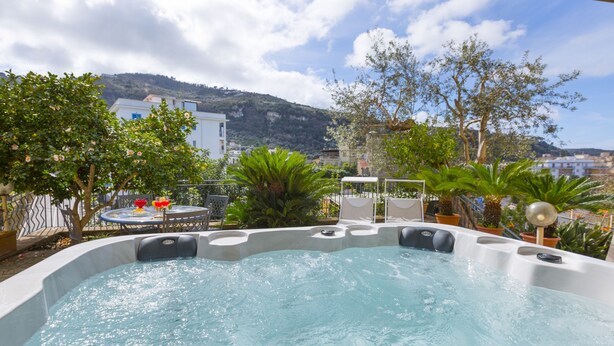 A hot tub with a view of a mountainous landscape, surrounded by potted plants and outdoor furniture. - Maison Wally in Sorrento (Sorrento)