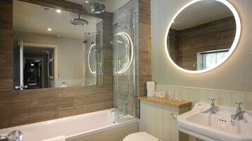 A modern bathroom with a glass-enclosed shower, a large mirror with a circular light, a bathtub, and a sink.