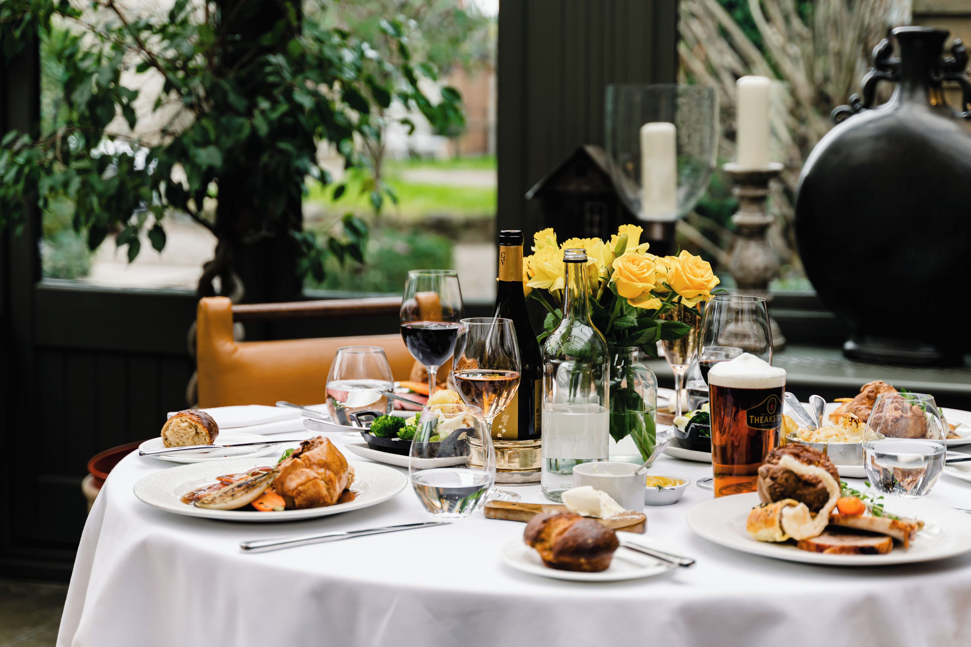 A dining table set with various dishes, glasses of wine, and a bottle of champagne.