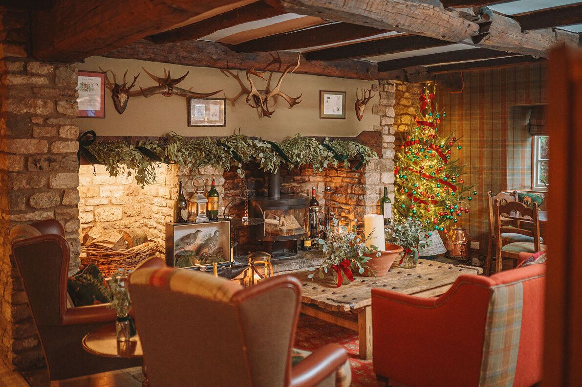 A cozy room with a stone fireplace, wooden beams, and a decorated Christmas tree.