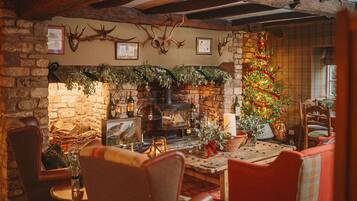 A cozy room with a stone fireplace, wooden beams, and a decorated Christmas tree.