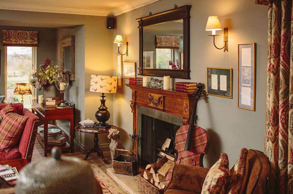 Una sala de estar acogedora con chimenea, un sofá rojo, una mesa de centro de madera y un perro.