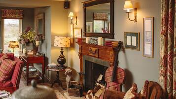 Una sala de estar acogedora con chimenea, un sofá rojo, una mesa de centro de madera y un perro.