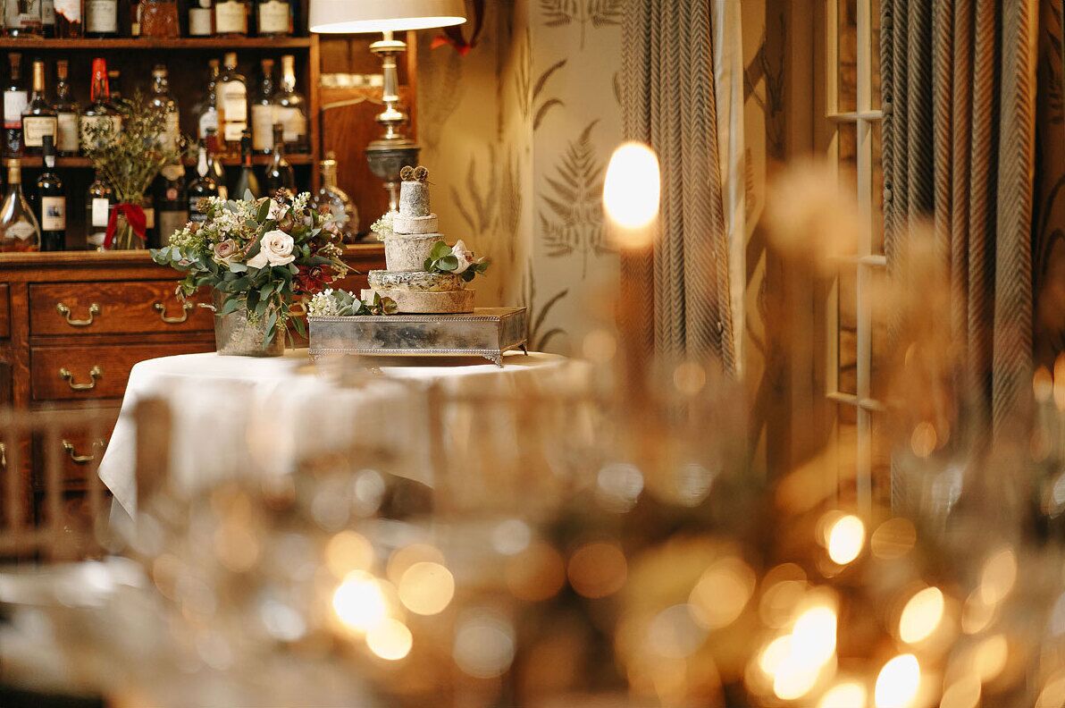 A bar area with a wine rack, a table with a cake, and a vase of flowers.