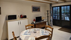 A dining area with a wooden table, chairs, a cabinet, and a painting on the wall. - 2 Pièces, Jardinet Sud, Calme, 1000 m Morgat (Crozon)