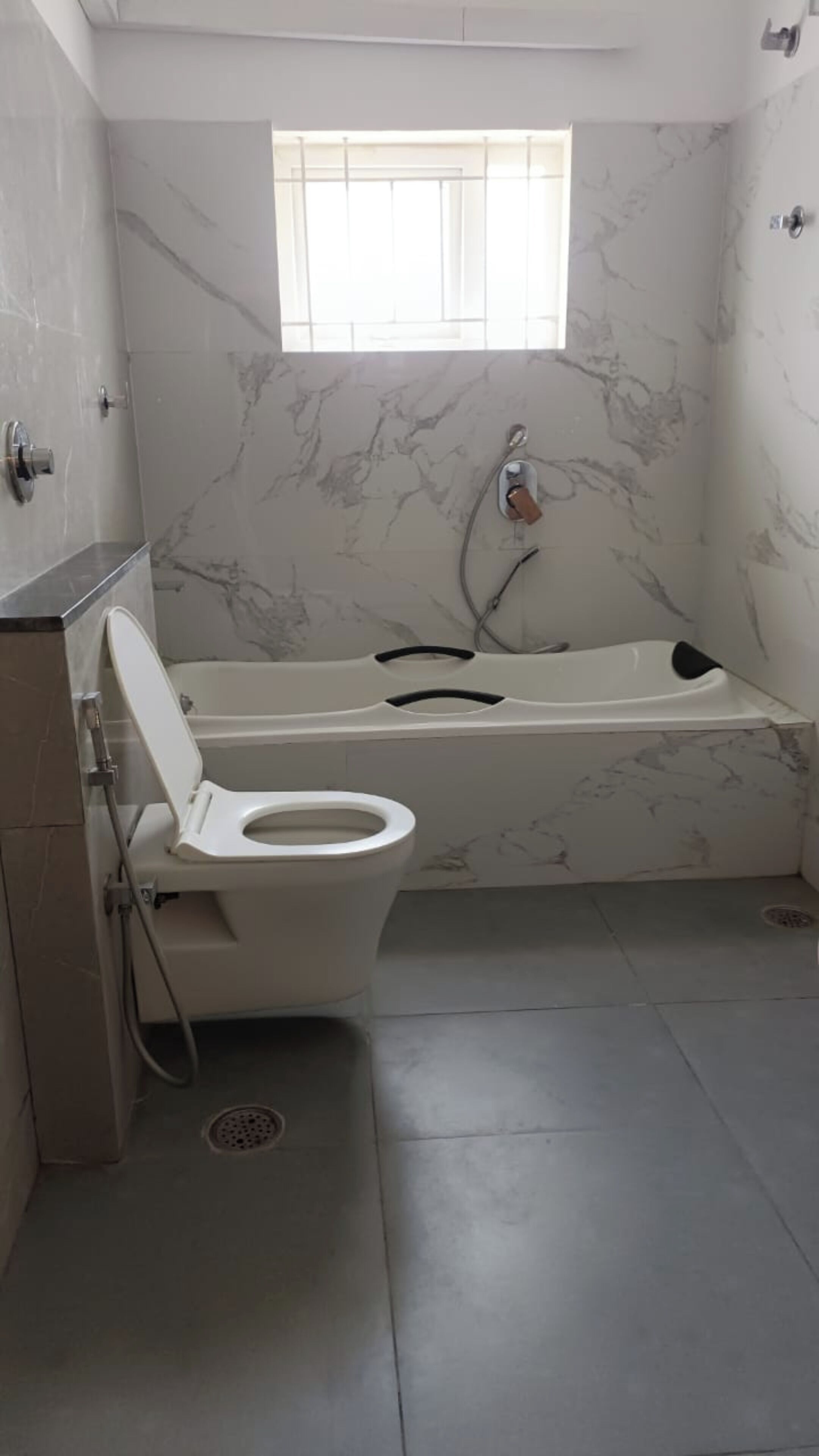 A bathroom with a bathtub, toilet, and a window.