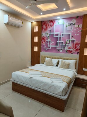 A modern bedroom with a bed, wooden headboard, and a decorative wall with floral patterns. - The Waves Hotel Sarjapura (Anekal)