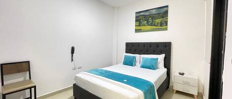 A bedroom with a bed, a chair, a bedside table, a nightstand, a painting, and a door.