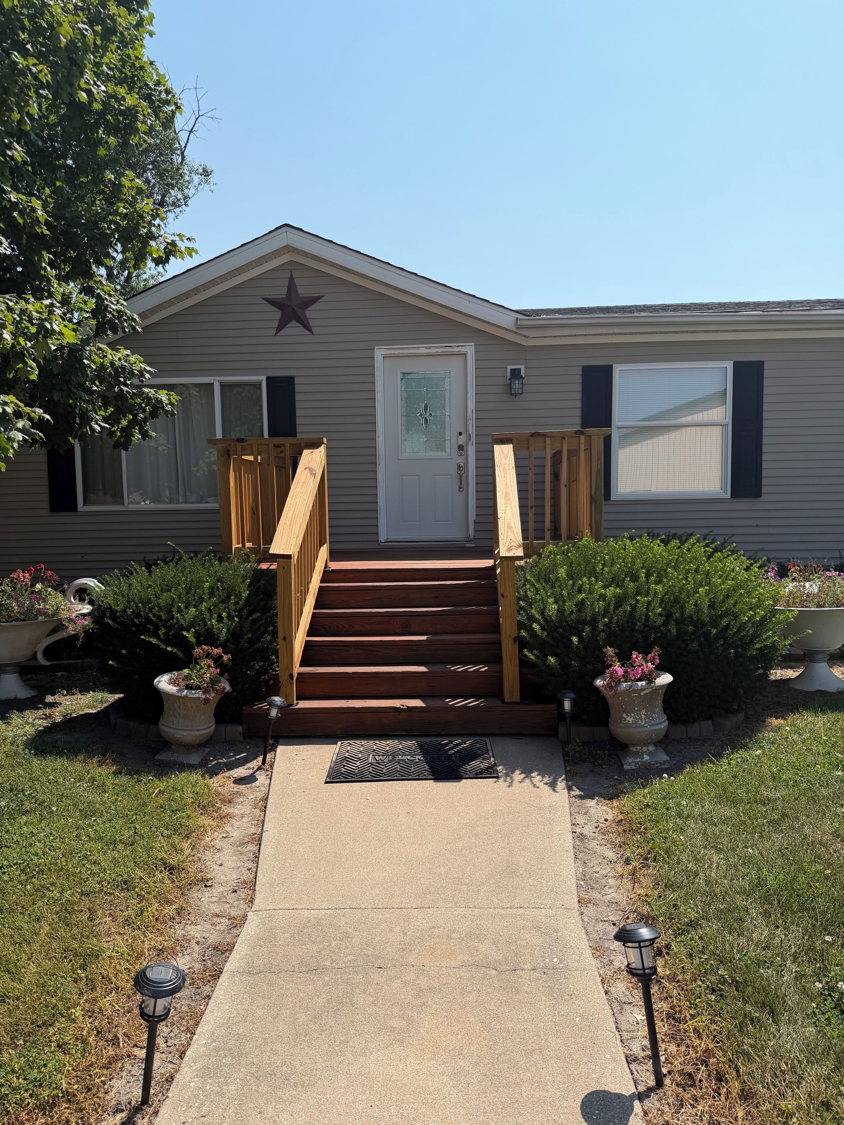 A single-story house with a front porch, a wooden staircase, and a star decoration on the wall.