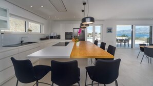 Une cuisine moderne avec un îlot central, des chaises noires et une vue sur l’extérieur.